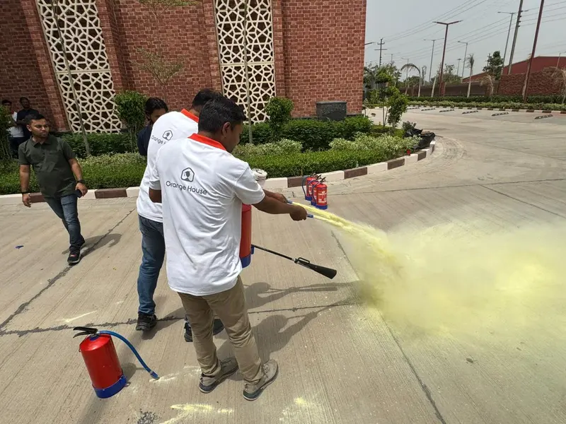 Employee discharging a dry powder fire extinguisher at ground level during on-site fire safety training