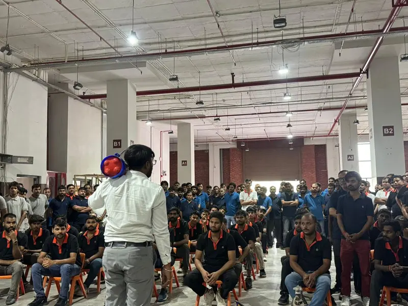 Instructor addressing seated employees during a fire safety awareness session inside a warehouse