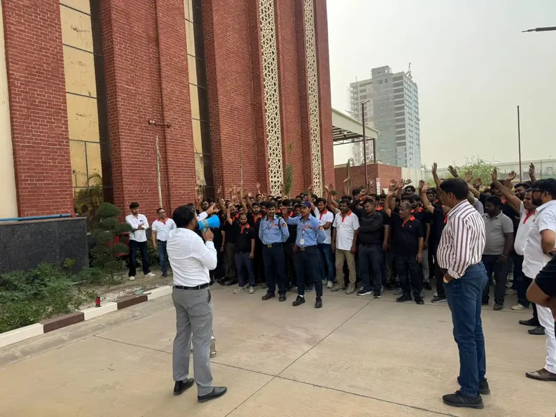 Employees raising their hands during a headcount at the assembly point in a fire evacuation mock drill